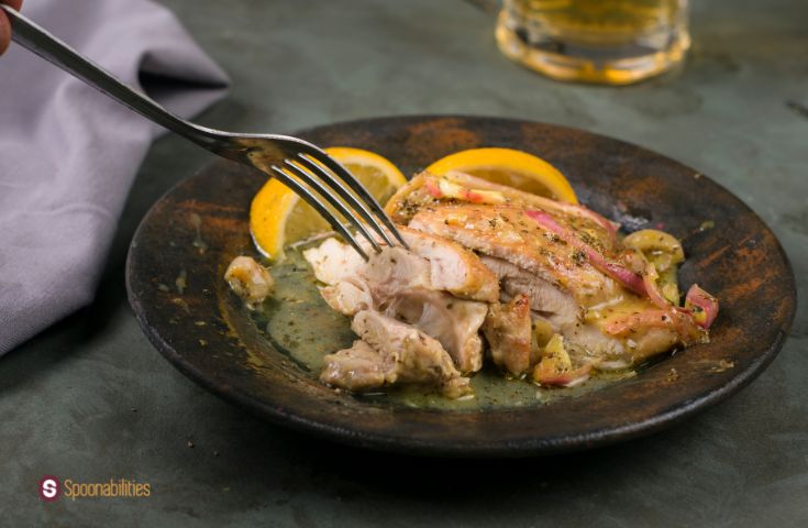 A photo of Baked Chicken Thighs with Honey Mustard Sauce, with lemons on the side and a fork on the chicken.