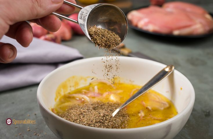 A photo of Honey Mustard Sauce in a marble bowl with a hand holding a measuring cup combining the ingredients.