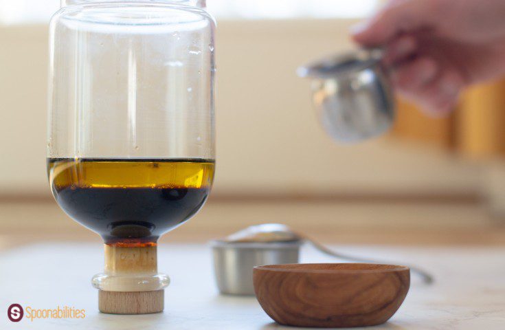 A photo of vinaigrette ingredients in a lidded jar and a small wooden bowl on the side