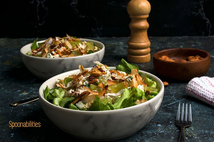 Two marble bowls of Rotisserie Chicken Salad with a fork, peppermill, and bowl of almonds.