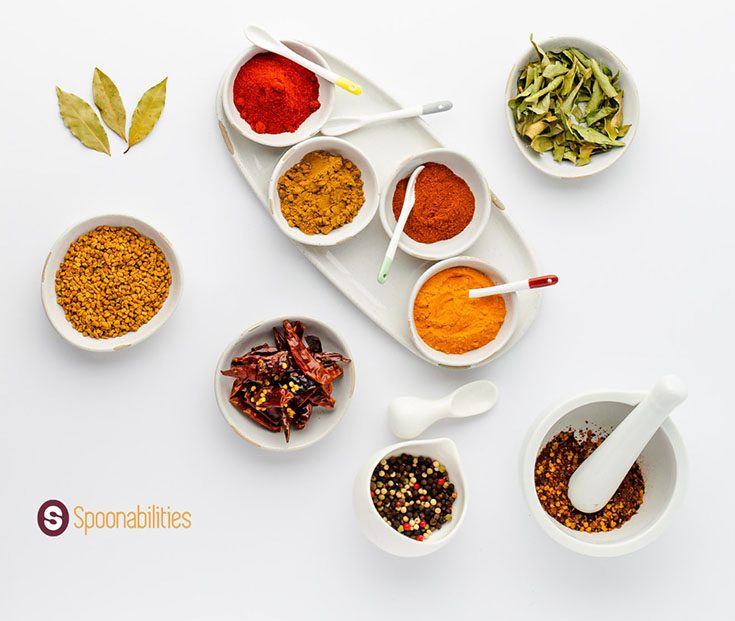 a photo of spices and salts in small white bowls with serving spoons