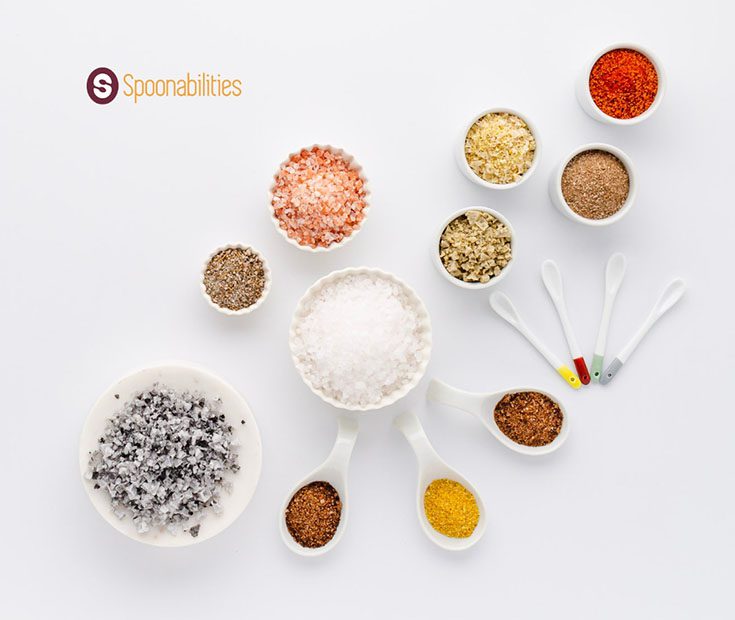 a photo of spices and salts in small white bowls with serving spoons