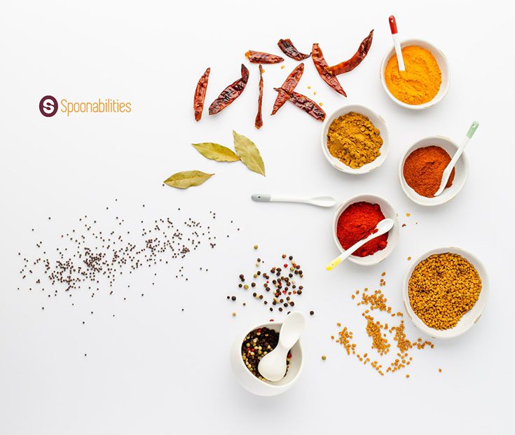 a photo of spices and salts in small white bowls with serving spoons