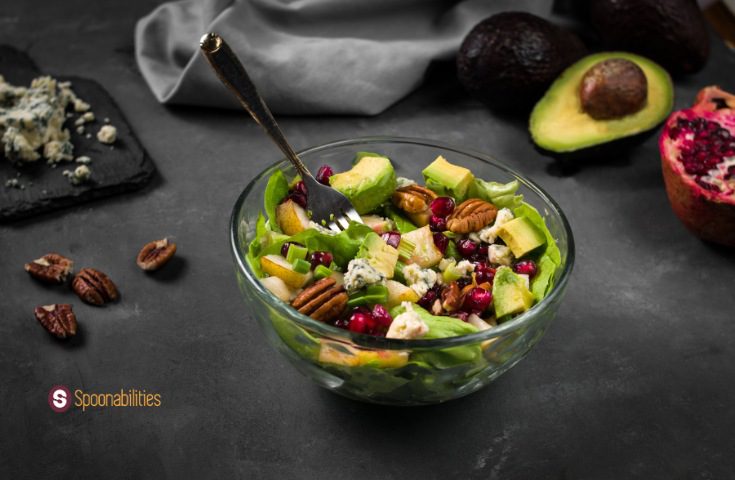 a photo of Honey mustard vinaigrette on butter lettuce pear salad in a clear bowl with some of the ingredients on the side