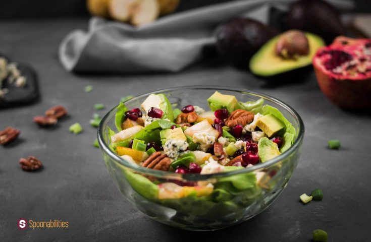 a close up photo of Honey mustard vinaigrette on butter lettuce pear salad in a clear bowl