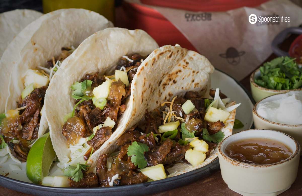 Tacos with pork carnitas filling with various dips and toppings