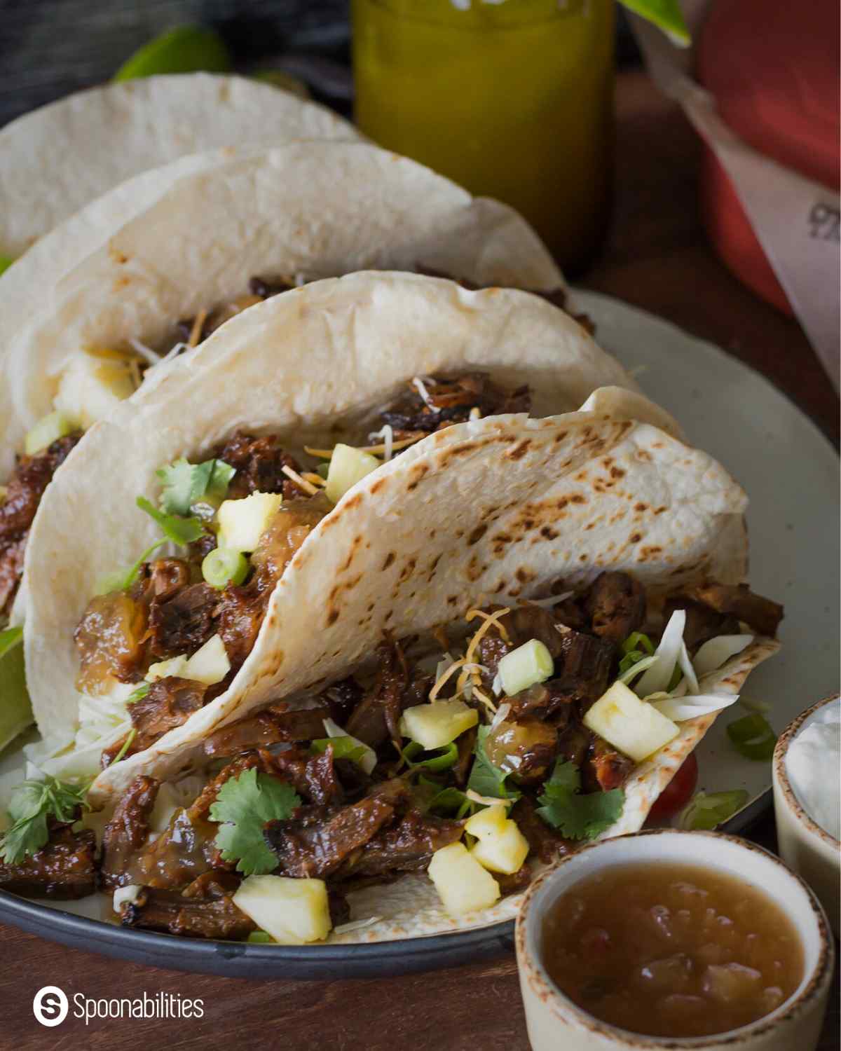 Pork carnitas in soft taco shells with sauce on the side