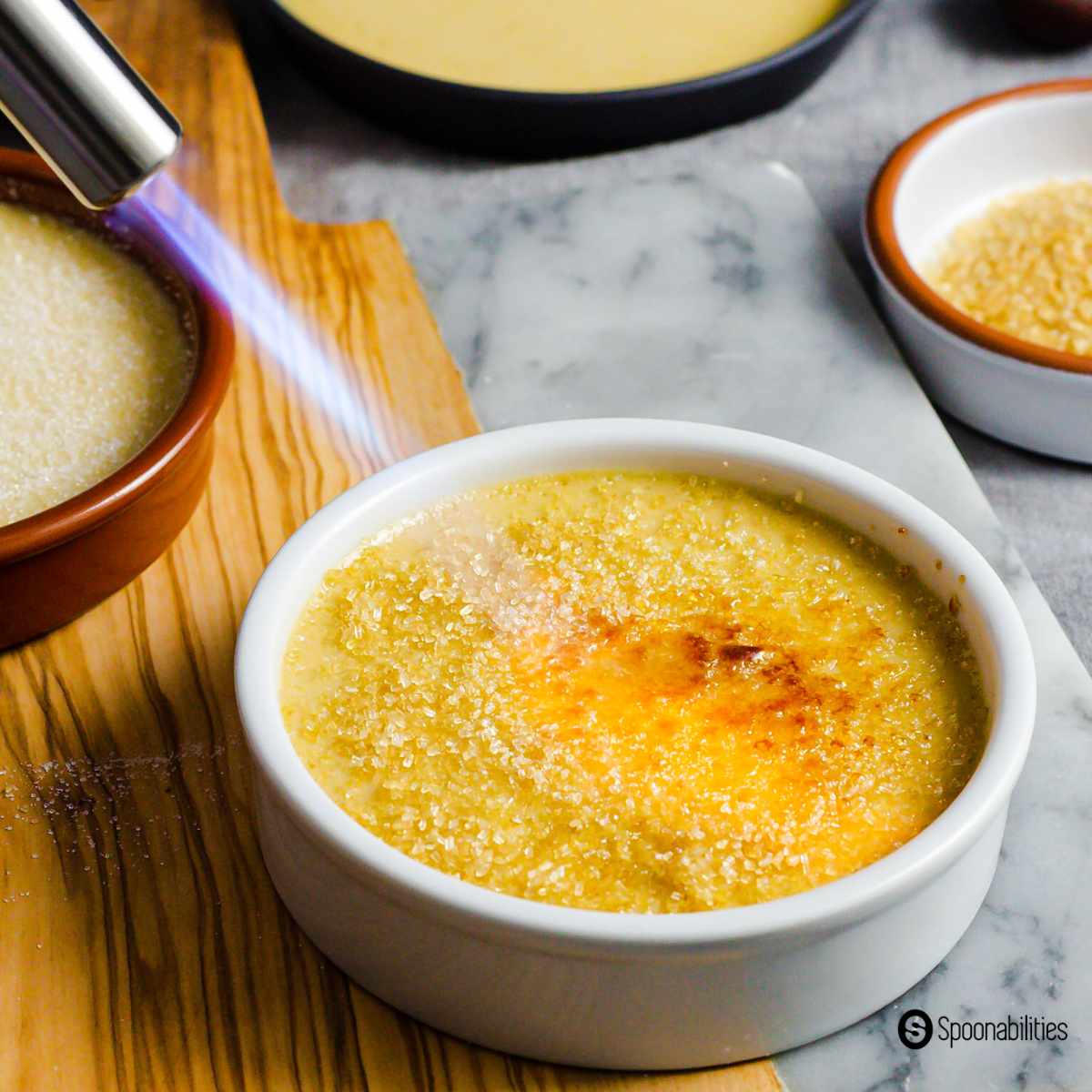 Caramelizing the sugar on top of the creme brulee with a kitchen torch