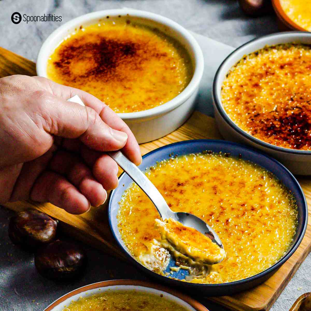 Scooping soft and creamy creme brulee from a blue baking dish