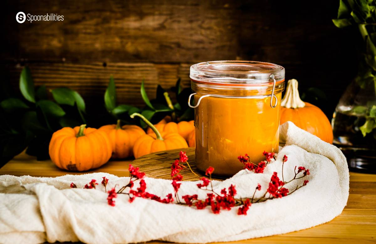 Pumpkin bisque in a jar with tiny pumpkins at the background