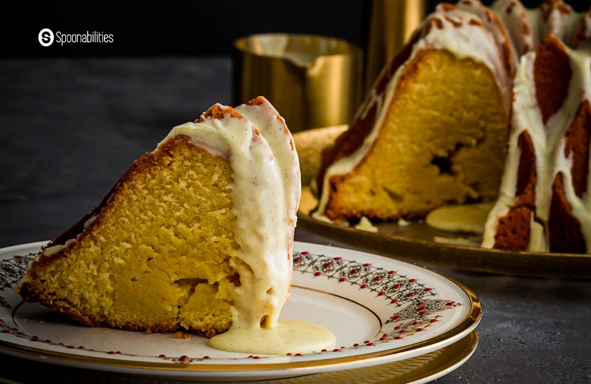 A slice of eggnog brandy cake on a white plate with gold trimming