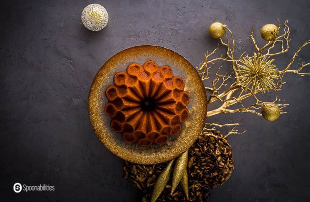 Brandy eggnog cake on a gold plate with gold festive decorations all around