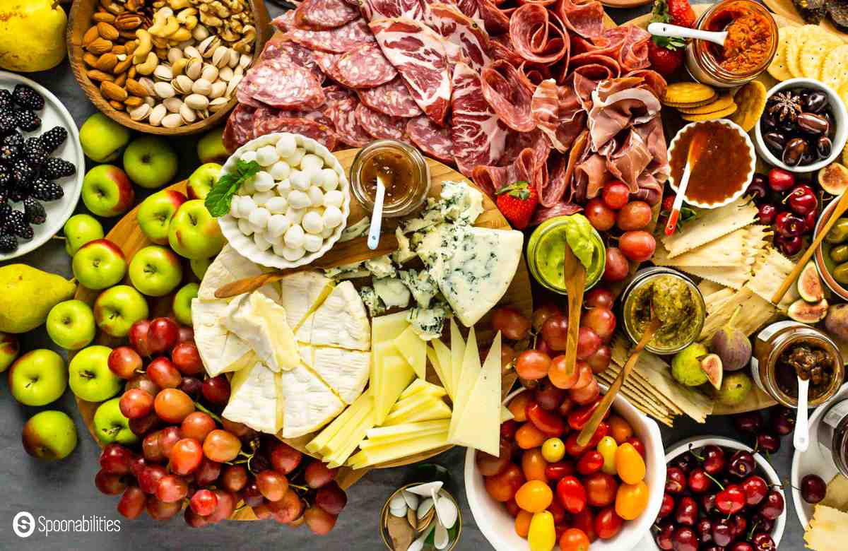 charcuterie spread with meats, fresh and dried fruits, different cheeses, crackers, nuts and spreads