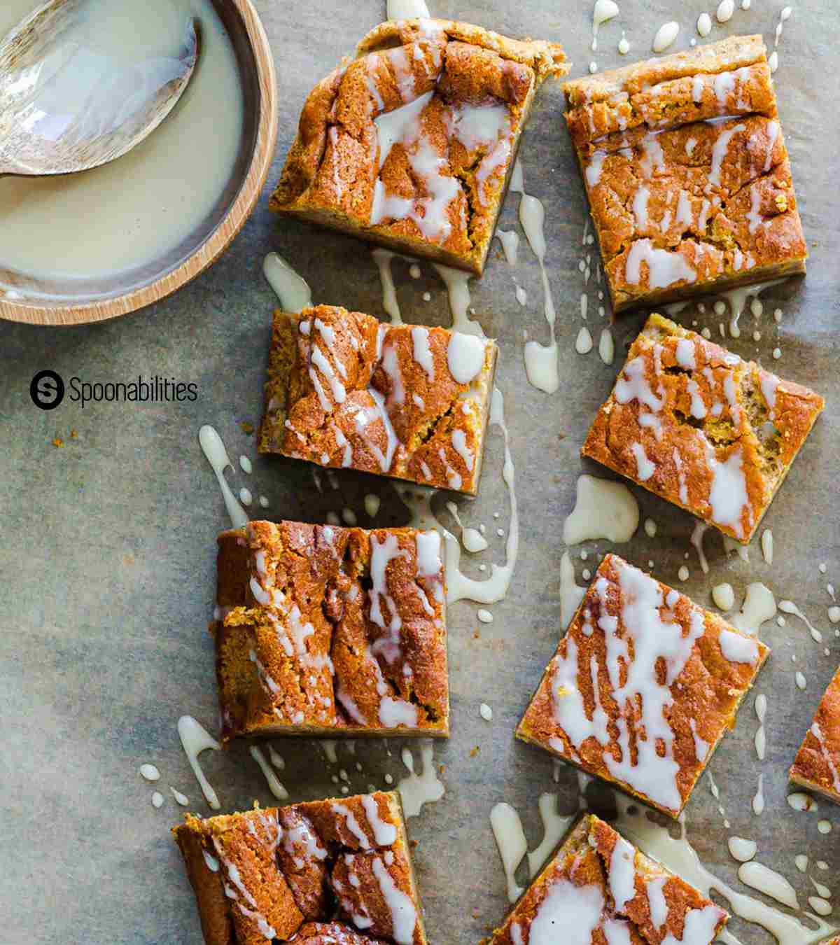 Pumpkin Magic Cake with white maple syrup drizzle in a small bowl with spoon at the left