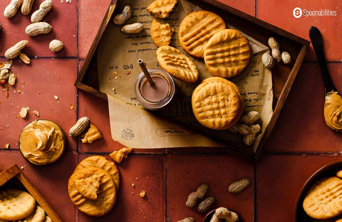 Best peanut butter cookies in a tray with chocolate milk and peanuts and peanut butter as decorative elements