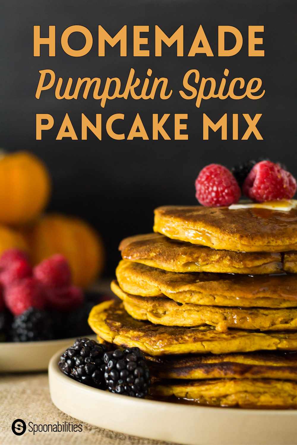 Pumpkin spice pancakes on a white plate with mixed berries and syrup