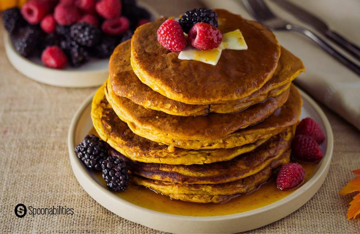 Stack of pumpkin spice pancakes with maple syrup and mixed berries