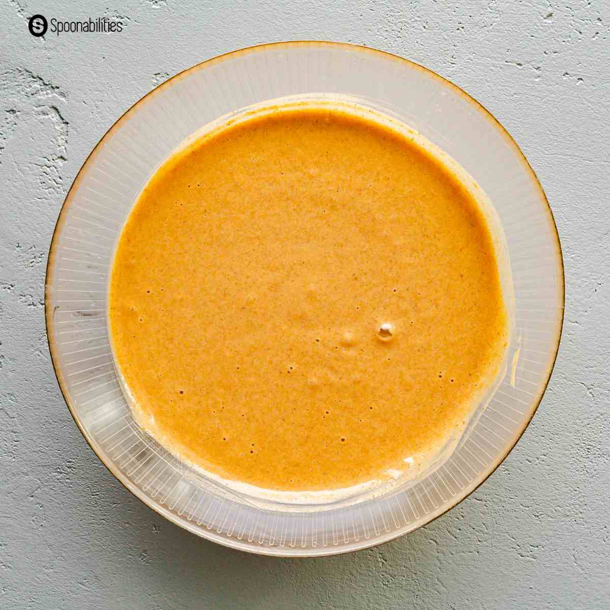 Batter for pumpkin roll cake in a clear mixing bowl