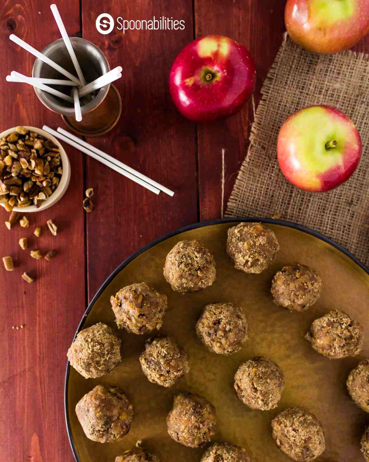 Top view of mini caramel apples on a platter with pecan in a small bowl and some red apples