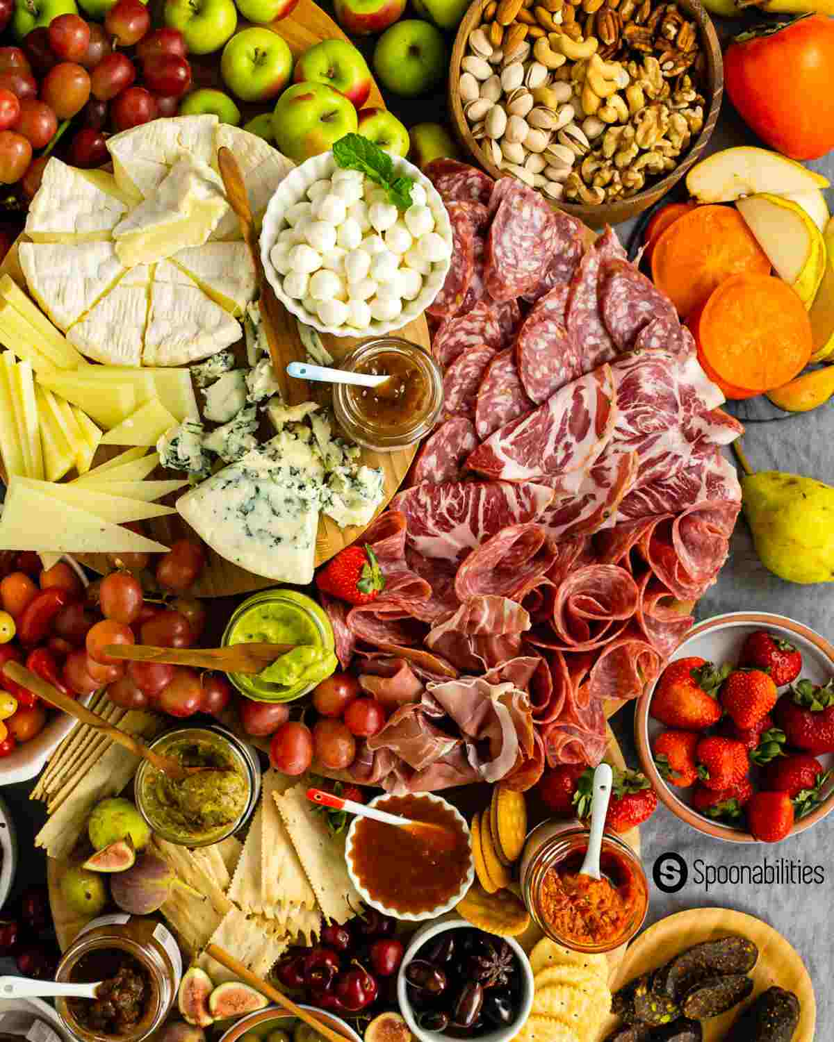 Charcuterie boards with cheeses, meat, bread and fruits and jars of spreads