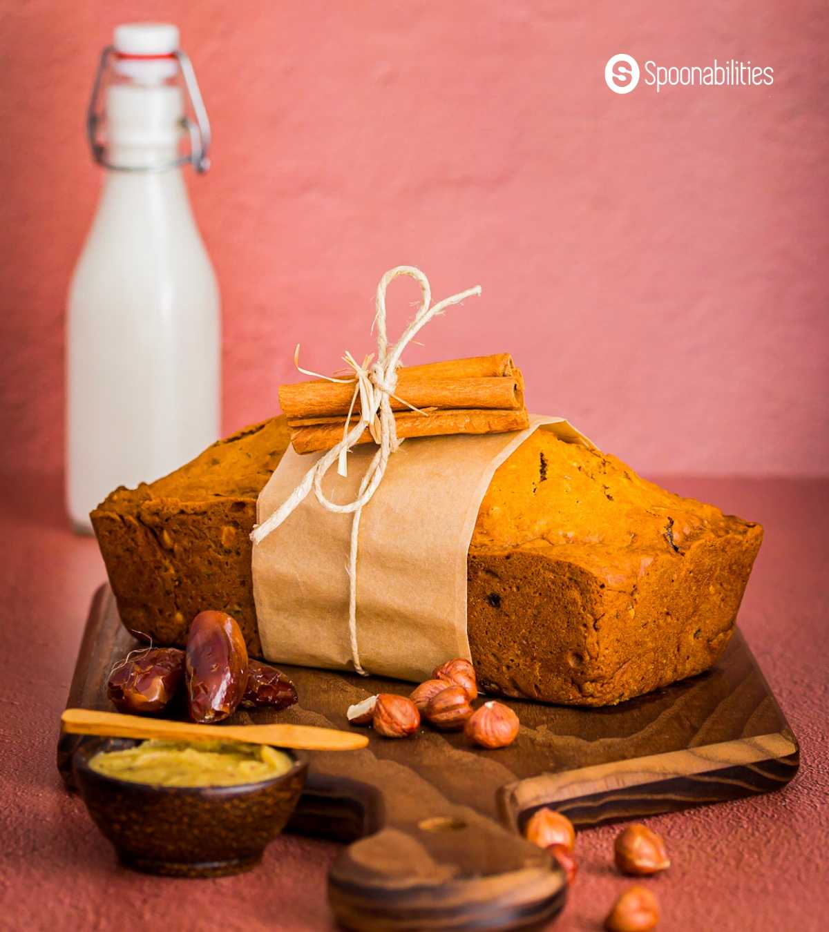 Pumpkin bread loaf with hazelnuts, dates and brown butter on a wooden chopping board