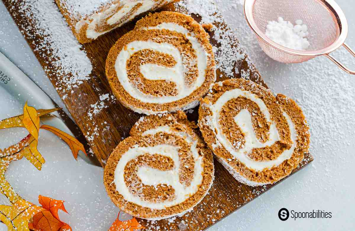 Pumpkin cake roll sliced on a wooden chopping board