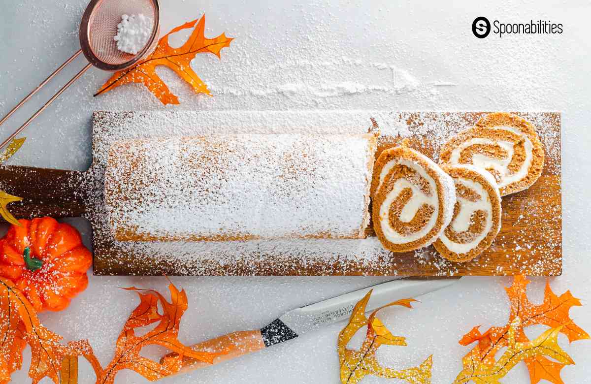 Pumpkin roll dusted with powdered sugar arranged with some fall theme decorations