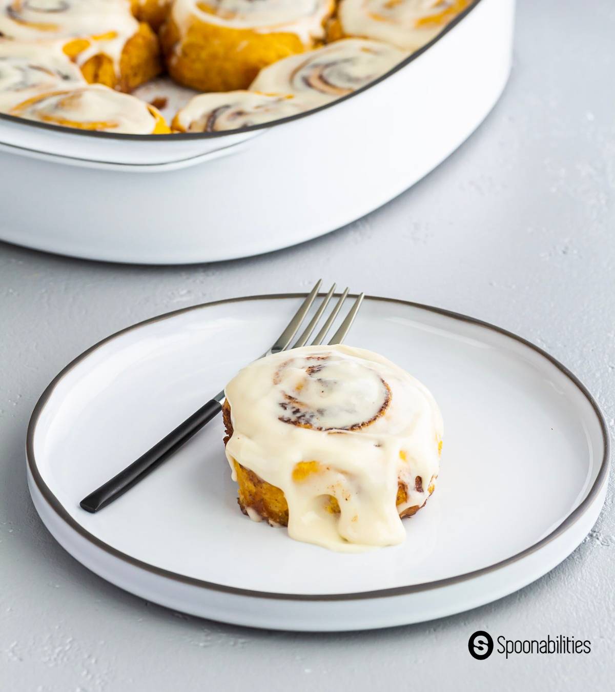 one cinnamon roll with icing on a plate
