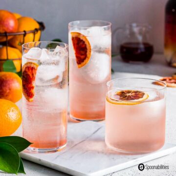 Three glasses of blood orange cocktail with ice and slices of blood orange