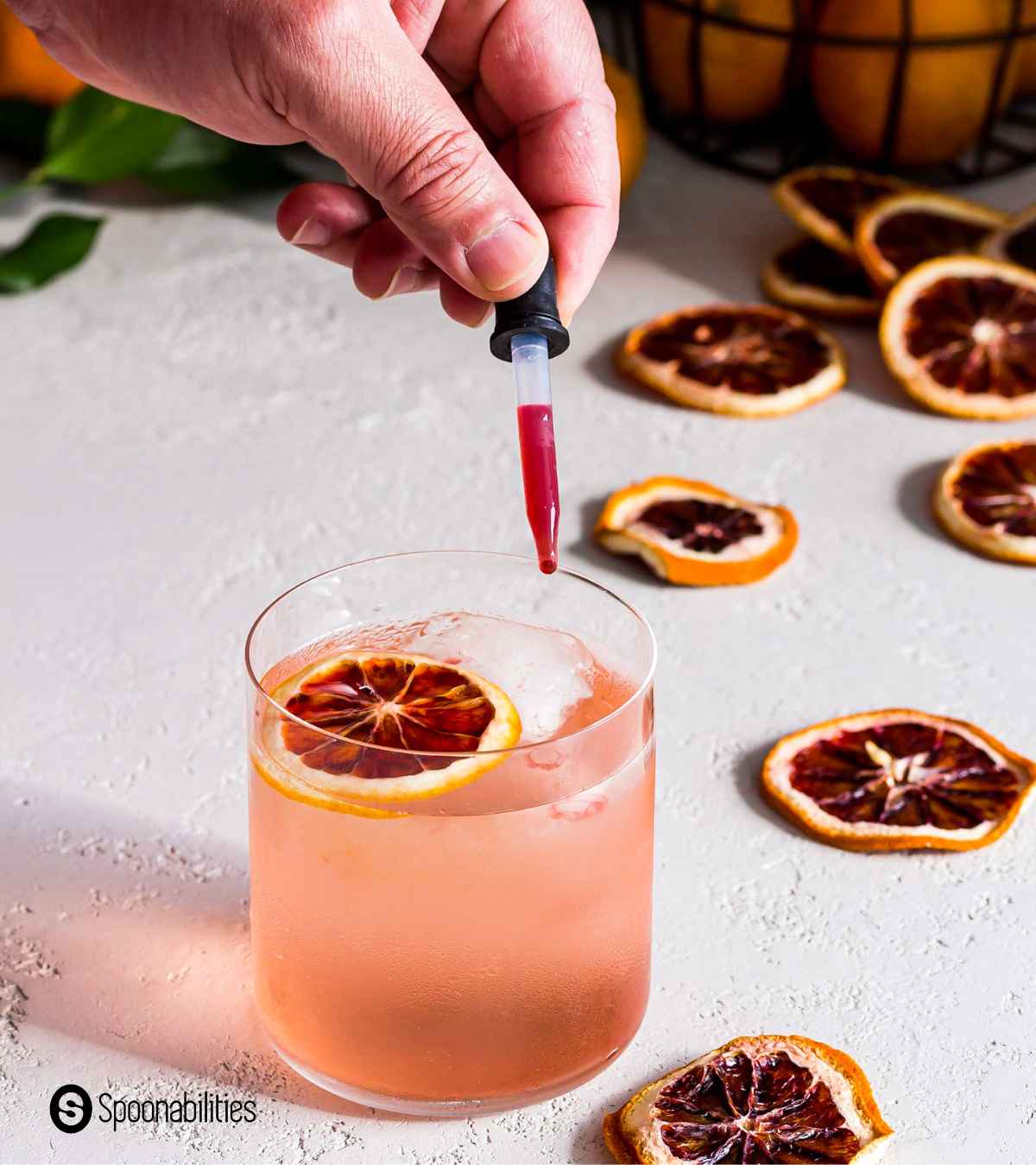 Adding fresh blood orange juice on a glass of blood orange cocktail with ice for more reddish color