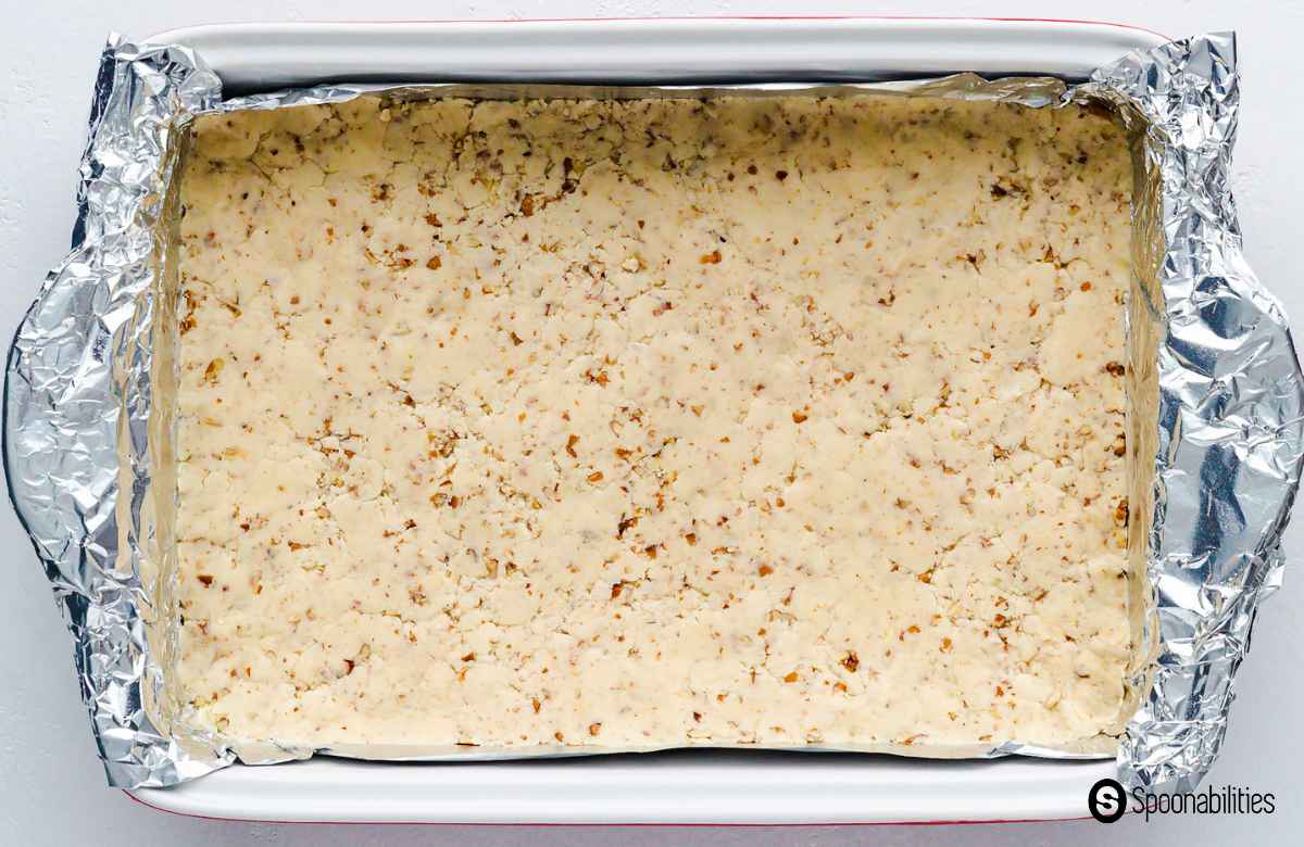 Pressed crust of the cheesecake bars in a baking dish