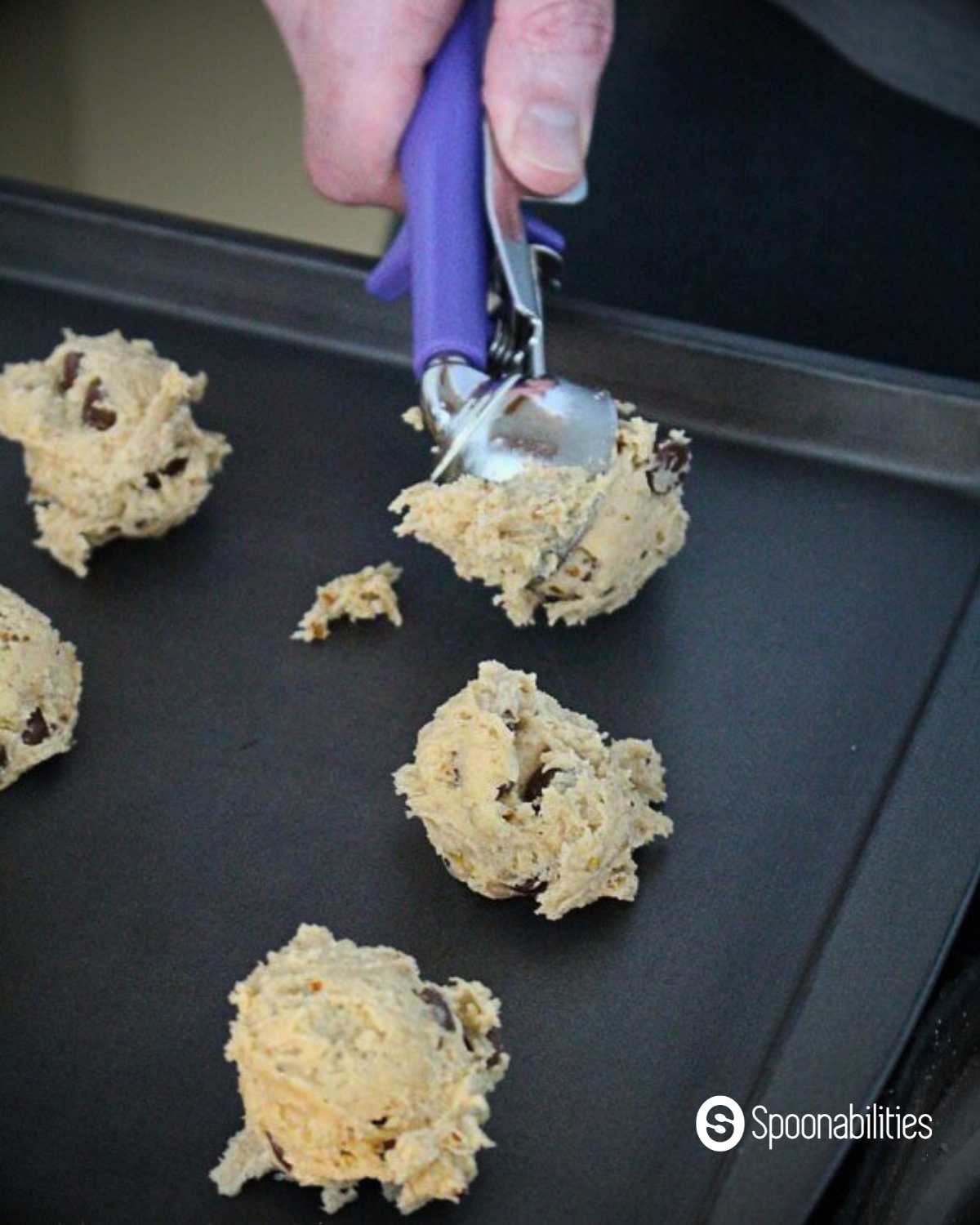 Scooping chocolate chip cookie dough on baking pan