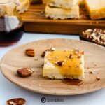 maple cheesecake on a wooden plate with crushed pecan toppings