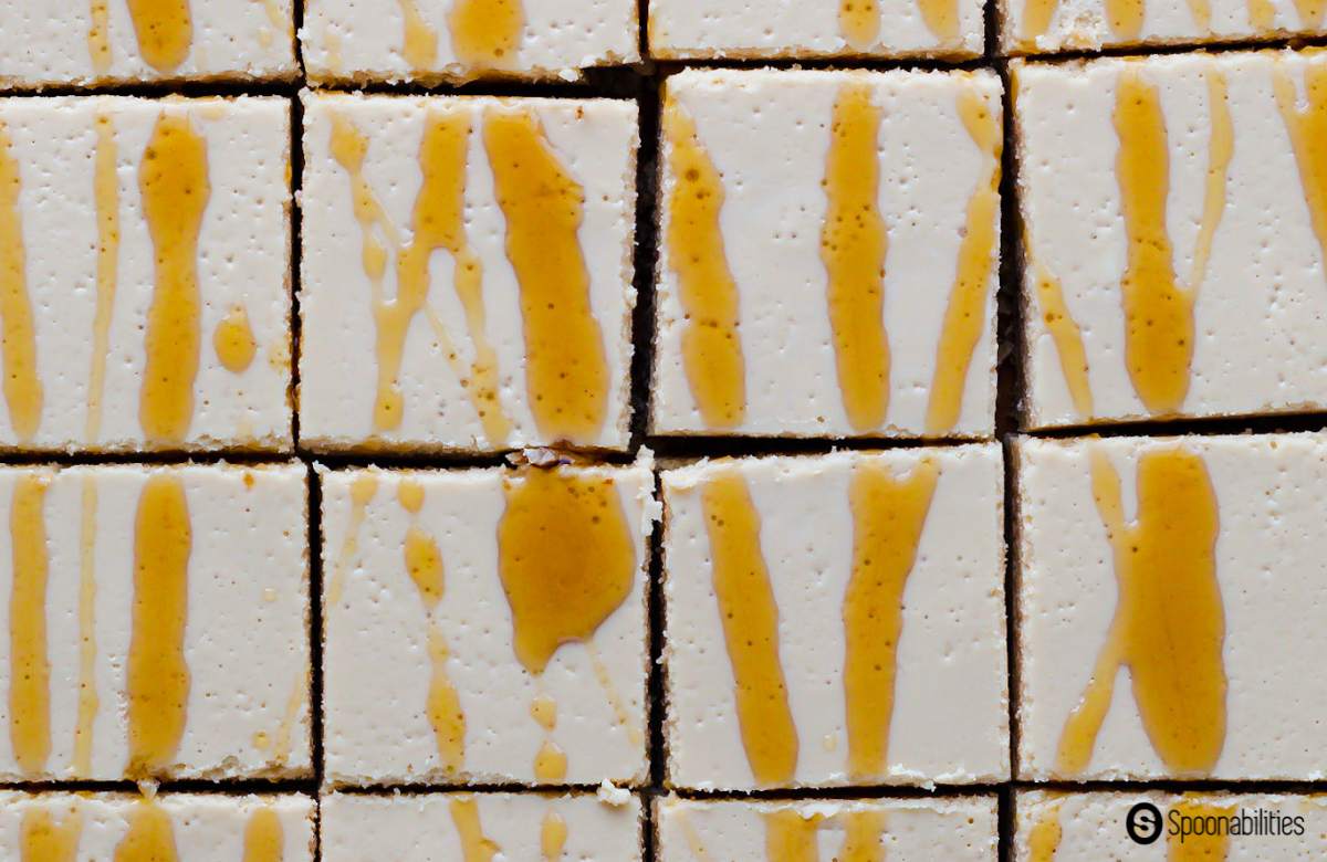 Close up of cheesecake bars cut into squares with maple drizzle on top