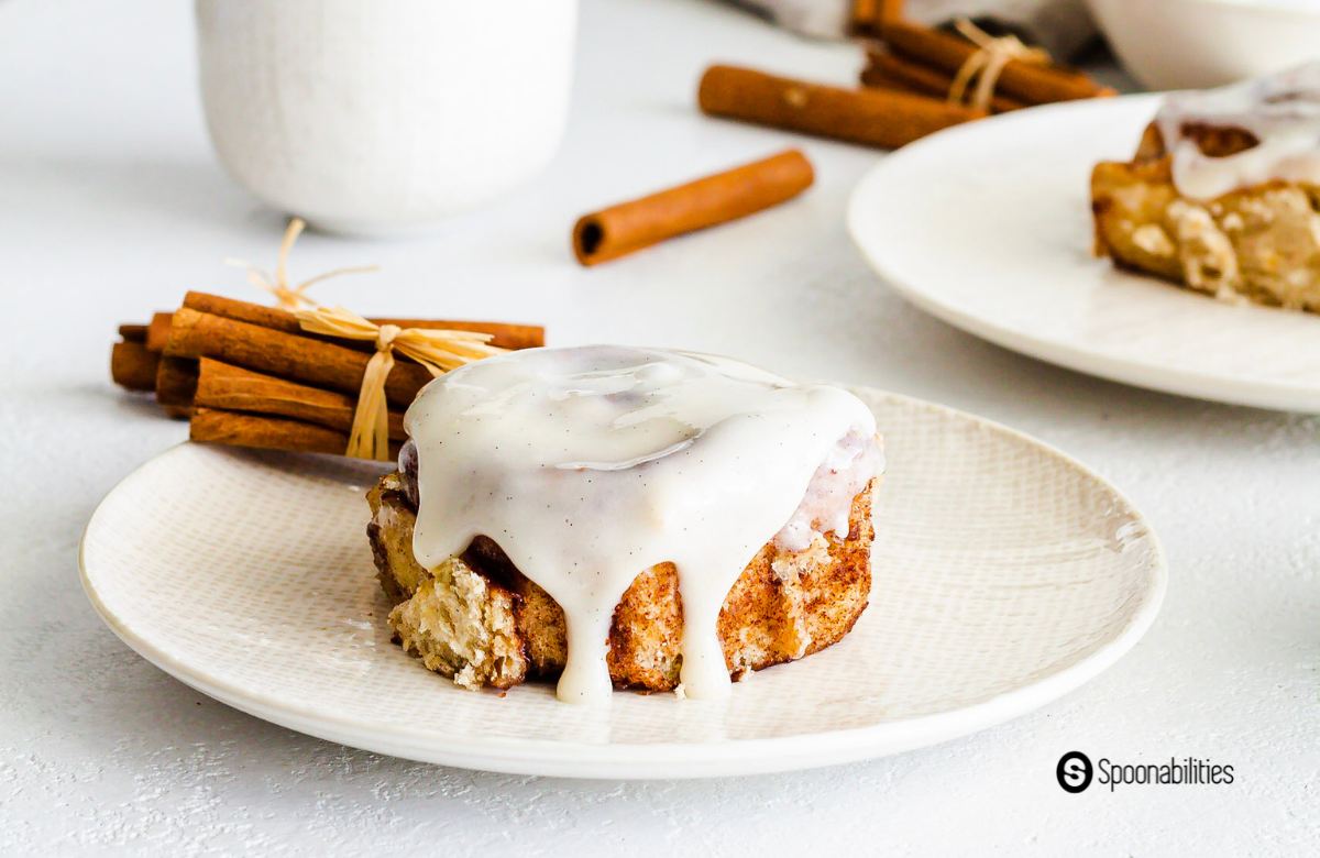 Sourdough cinnamon roll on a plate with cinnamon sticks in the background