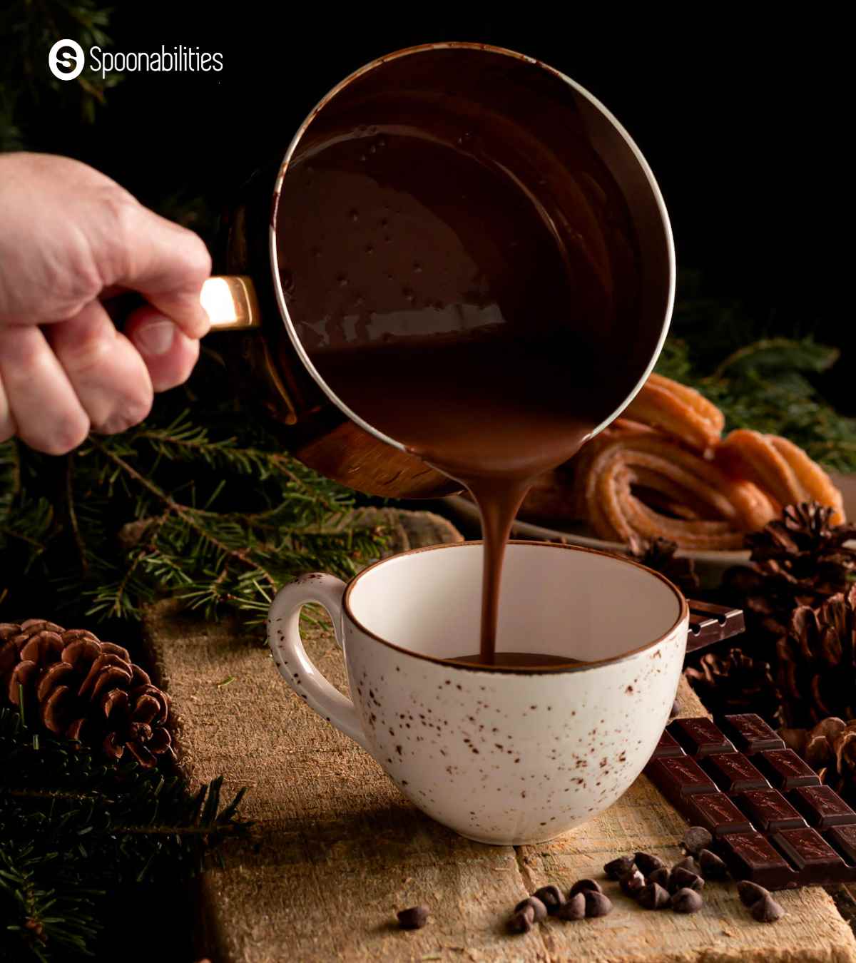 Pouring hot cocoa from a saucepot into a white cup