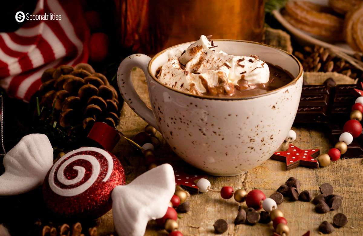 A cup of hot chocolate with whipped cream topping among Yuletide ornaments around