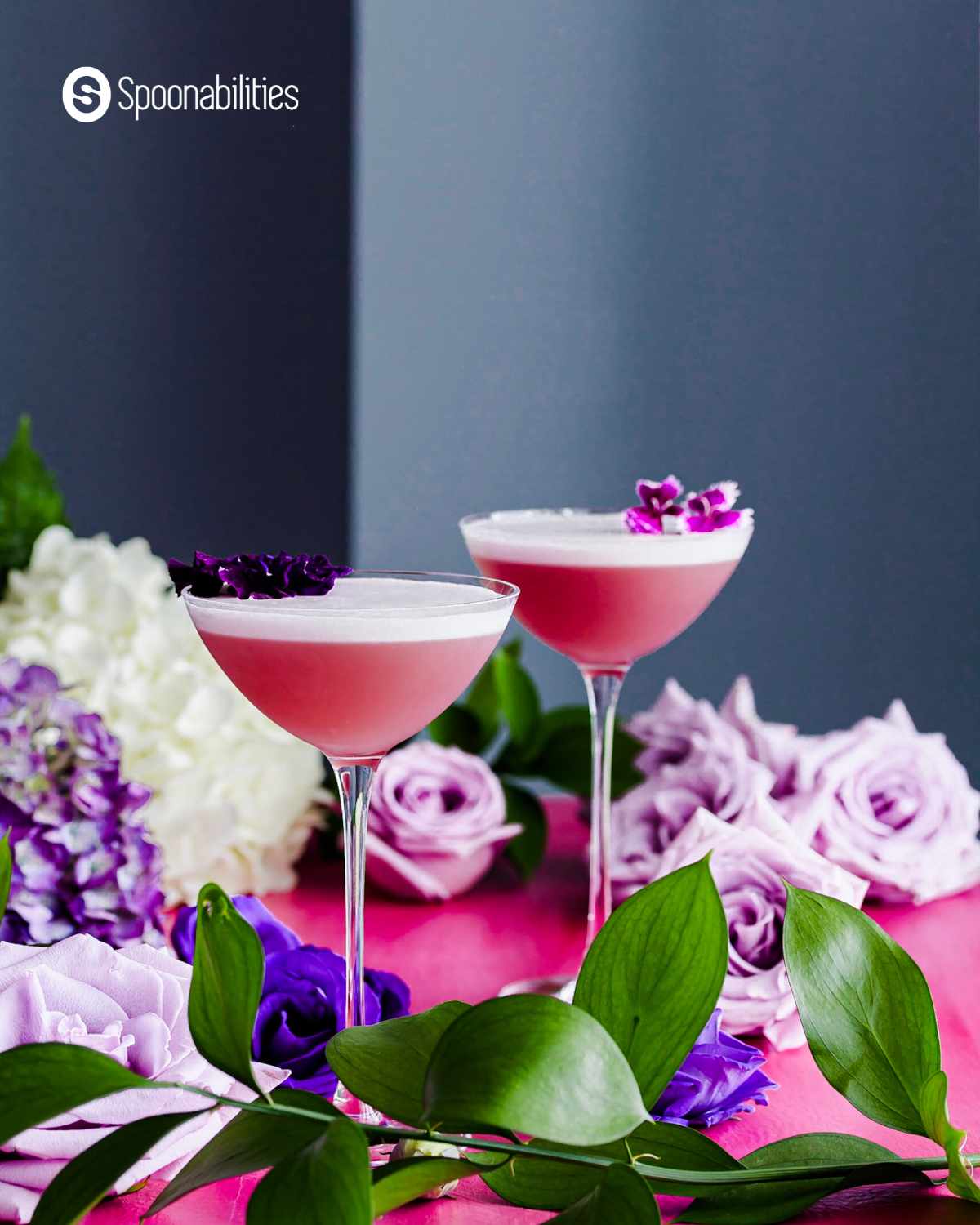 Gin violette cocktail in glasses with violet colored flowers as garnish